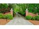 Elegant gated entrance with brick pillars leading to a long, private driveway through lush greenery at 4500 Candacraig, Alpharetta, GA 30022