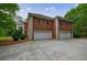 Rear exterior view of a red brick home with a three-car garage and well-manicured lawn at 4500 Candacraig, Alpharetta, GA 30022