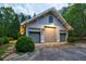 Three-car garage featuring carriage doors, side lights, and a stylish gable window, nestled in a beautifully landscaped yard at 4500 Candacraig, Alpharetta, GA 30022