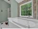 Relaxing bathroom featuring a soaking tub next to a window offering a scenic view, and shower at 2582 Oak Bluff Dr, Dacula, GA 30019