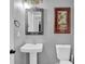 Cozy bathroom with a pedestal sink, mirror, toilet, and decorative artwork on gray walls at 2582 Oak Bluff Dr, Dacula, GA 30019