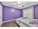 Stylish purple bedroom featuring hardwood floors, ceiling fan, and a comfortable queen-sized bed at 5008 Bethpage Dr, Suwanee, GA 30024