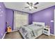 Inviting purple bedroom with hardwood floors, ceiling fan, guitar, and queen-sized bed at 5008 Bethpage Dr, Suwanee, GA 30024