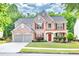 Beautiful two-story brick home with red shutters, landscaped front yard, and spacious garage at 5008 Bethpage Dr, Suwanee, GA 30024