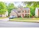 Two-story brick home with red accents, lush landscaping, and a two-car garage at 5008 Bethpage Dr, Suwanee, GA 30024