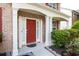 Inviting brick home entrance featuring a red door and decorative white pillars at 5008 Bethpage Dr, Suwanee, GA 30024
