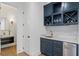 Chic bar area with custom blue cabinetry, wine storage, a mini fridge, and a marble countertop with sink at 120 Nezhat Pl, Sandy Springs, GA 30350