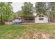 Large backyard featuring a covered deck, fire pit, and spacious lawn surrounded by mature trees offering outdoor entertainment at 4100 Springlake Cir, Buford, GA 30519