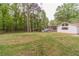 Spacious backyard featuring a large grassy area, a wooden fence line, and a white house with a charming covered porch at 4100 Springlake Cir, Buford, GA 30519
