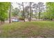 Sprawling backyard featuring mature trees, green grass, a fire pit seating area, and covered back deck providing ample outdoor space at 4100 Springlake Cir, Buford, GA 30519