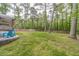 Expansive backyard featuring a fire pit with Adirondack chairs, a covered deck, and a lush green lawn with mature trees at 4100 Springlake Cir, Buford, GA 30519