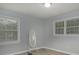 This bright bedroom features two windows with blinds, a full length mirror, and wood-look flooring at 6892 Autumn Hills Dr, Douglasville, GA 30135
