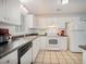 Well-lit kitchen featuring white cabinets, appliances, and tile flooring, providing a functional cooking space at 6892 Autumn Hills Dr, Douglasville, GA 30135