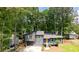 Scenic shot of a modern two-story home with a dark gray exterior, a black garage door, a green lawn, and mature trees at 805 Wayside Dr, Lawrenceville, GA 30046