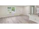 Renovated living room featuring gray laminate flooring, white walls, a window and a partial view of the kitchen at 1030 Brockdell Ct, Norcross, GA 30093