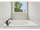Modern bathtub with a stylish faucet set and a view of nature through the window at 1701 Aircraft S Dr, Marietta, GA 30060