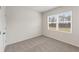 This bedroom features a window overlooking a yard, neutral carpet, and white walls at 321 Arwen Dr, Mcdonough, GA 30252