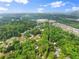 Aerial view of a residential area featuring tree-lined streets, various home styles, and a commercial area in the distance at 1620 Bluewater Ct, Cumming, GA 30041