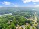 Stunning aerial view of a wooded community near a lake with blue skies and scattered clouds at 1620 Bluewater Ct, Cumming, GA 30041