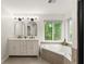 Bathroom featuring a double vanity, tile floors, and a large soaking tub overlooking a private wooded yard at 1620 Bluewater Ct, Cumming, GA 30041