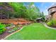 Beautifully landscaped backyard with a covered patio and outdoor kitchen is bordered by mature trees and gardens at 31 Brownson Ct, Acworth, GA 30101
