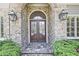 Elegant front door with stone surround, decorative glass, and flanking sconces at 5118 Greythorne Ln, Marietta, GA 30068
