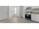 Bright eat-in kitchen featuring all white cabinets, stainless appliances, gray wood floors, and granite countertops at 6093 Camden Forrest Ct, Riverdale, GA 30296