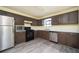 Well-lit kitchen with modern stainless steel appliances, brown cabinets, and gray vinyl floors at 4157 Lake Mist Nw Dr, Kennesaw, GA 30144