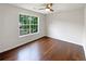 Cozy bedroom with hardwood floors, a ceiling fan, and a large window providing ample natural light at 541 Mckenzie Ave, Stockbridge, GA 30281