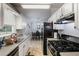 Well-lit kitchen with a view of the dining area, black appliances and white cabinets at 379 Villa Rosa Way, Temple, GA 30179