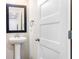 A pedestal sink and black framed mirror with a view into the water closet add charm to this half bath at 415 Paynes Lake Rd, Carrollton, GA 30116