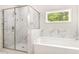 Elegant bathroom featuring a glass enclosed marble shower, garden tub, and a window with green tree views at 415 Paynes Lake Rd, Carrollton, GA 30116