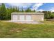 Large metal outbuilding with three garage doors and a walk-in door on a well-maintained lawn at 415 Paynes Lake Rd, Carrollton, GA 30116