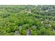 An aerial view of a wooded residential neighborhood with lush greenery and a lake in the distance at 745 Devon Hill Ct, Roswell, GA 30075
