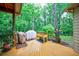 Wood deck with grill and bench overlooking the lush, wooded backyard with overhead string lights at 745 Devon Hill Ct, Roswell, GA 30075