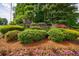 Entrance to Hamilton Commons neighborhood featuring stone wall, mature landscaping, and colorful flowers at 745 Devon Hill Ct, Roswell, GA 30075