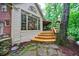 Sunroom exterior boasts wooden deck, steps and beautiful wall of windows overlooking the lush, wooded backyard at 745 Devon Hill Ct, Roswell, GA 30075