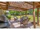 Relaxing back patio with wooden pergola, seating area, and grill, perfect for outdoor entertaining at 45 Pine Tree Dr, Mcdonough, GA 30252