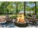 Inviting stone fire pit with Adirondack chairs, set against a picturesque wooded backdrop at 45 Pine Tree Dr, Mcdonough, GA 30252