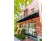 Close up of a multi-story brick townhome with a small balcony, large windows, and landscaping at 89 E Andrews Nw Dr, Atlanta, GA 30305