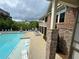 Community pool with lounge chairs and sunbeds next to a multi-story brick building with outdoor terraces and manicured landscaping at 2251 Nancy Creek Dr, Atlanta, GA 30341