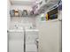 Functional laundry room with full-size washer and dryer, storage shelves, and a white door at 537 Daffodil Ln, Mcdonough, GA 30253