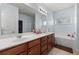 Bathroom features double sinks, wood cabinets, bathtub, and tiled floors at 1612 Nations Trl, Riverdale, GA 30296