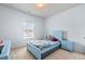 A bedroom with a blue bed, nightstand, carpeted floors, and a large window at 1612 Nations Trl, Riverdale, GA 30296