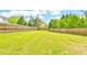 Expansive backyard with lush green grass, a wooden fence, and mature trees at 2727 Lost Mill Trce, Buford, GA 30519