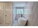 Soaking tub with a window, marble floors and walls at 3880 Northpoint Dr, Marietta, GA 30062