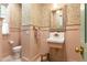 Quaint powder room featuring patterned wallpaper, pink wainscoting, and a unique pedestal sink, adding vintage charm at 4785 Brinkley Ln, Atlanta, GA 30342