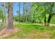 Spacious backyard featuring a lush green lawn, mature trees, and partial fence at 1660 Mallard Cir, Conley, GA 30288