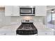 Close-up of kitchen featuring stainless steel range, microwave, and marble countertops at 1660 Mallard Cir, Conley, GA 30288