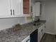 Close-up of the kitchen featuring granite countertops, a stainless steel sink, and white cabinets at 257 E Simon Nw Ter, Atlanta, GA 30318